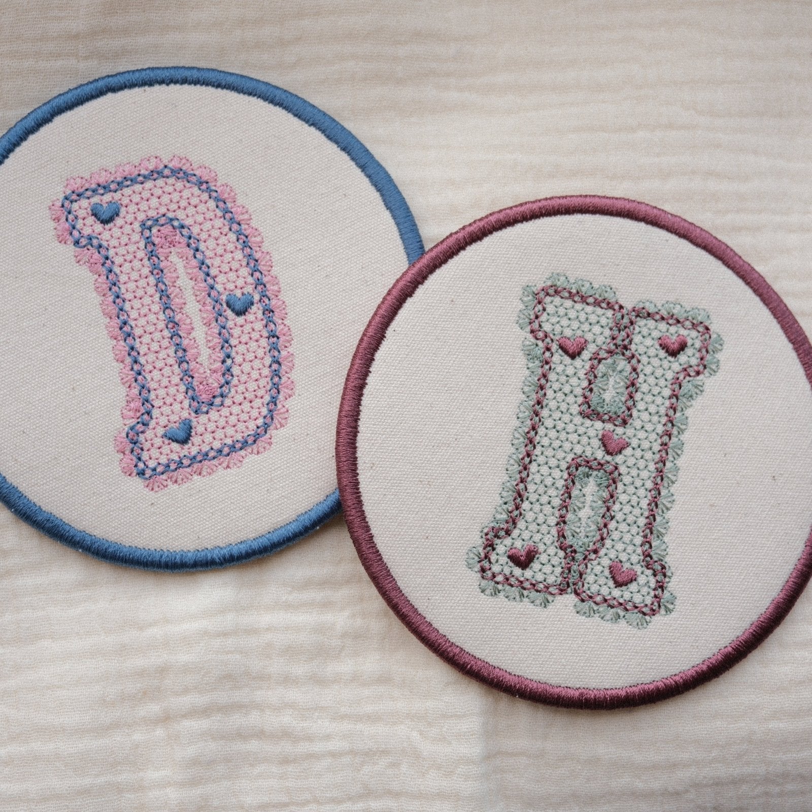 Pair of personalised embroidered coasters with lace effect initials D and H in pastel thread colour combinations